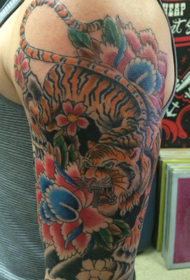 Japanese-style tiger with peonies and cherry blossoms on an upper arm